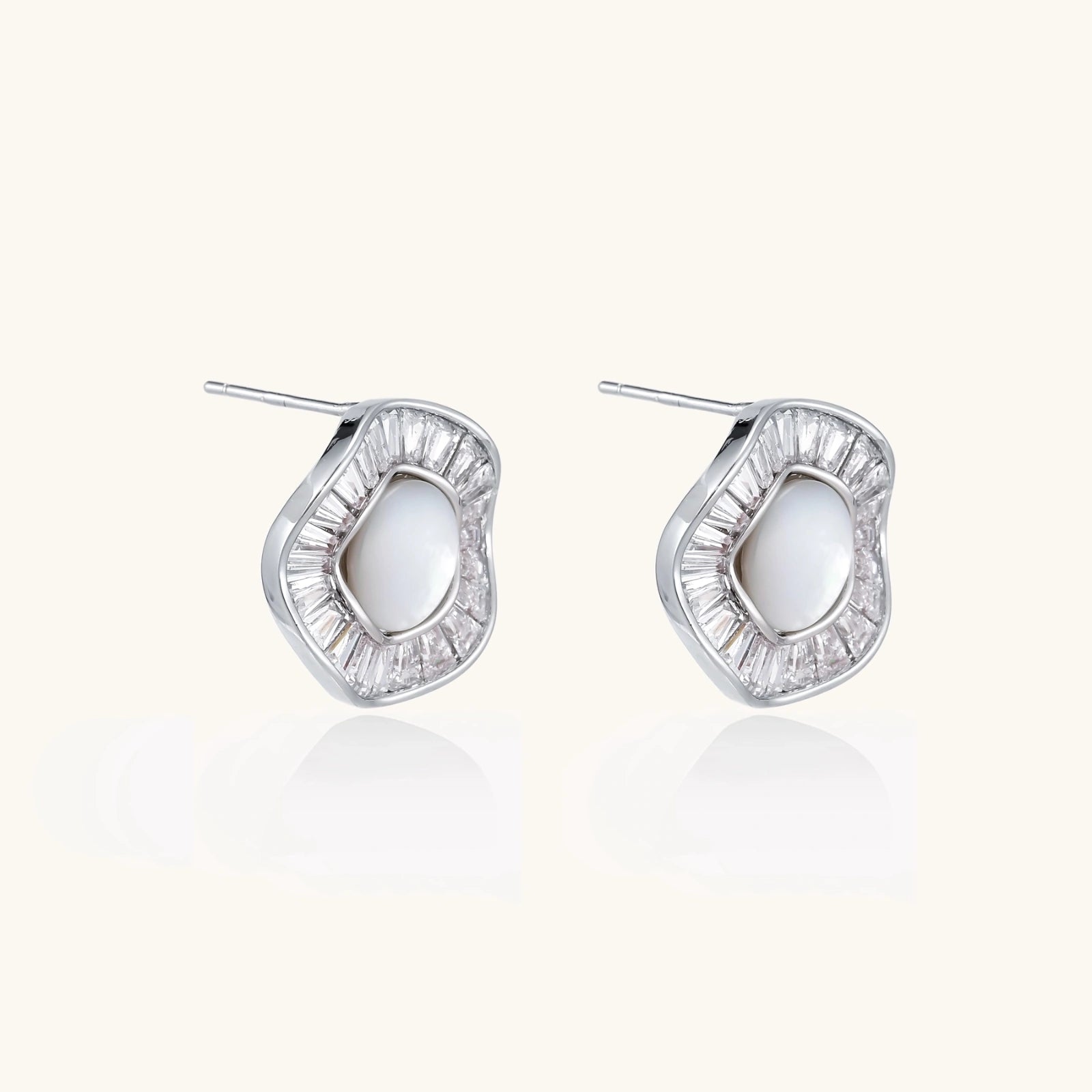 White gold-plated stud earrings with iridescent pearl centers surrounded by baguette crystal halos on white background.