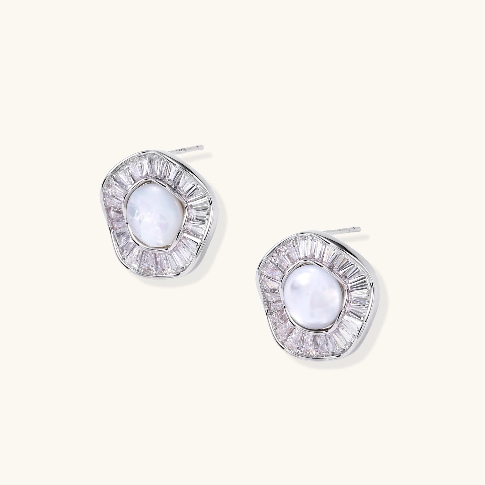 White gold-plated stud earrings with iridescent pearl centers surrounded by baguette crystal halos on white background.
